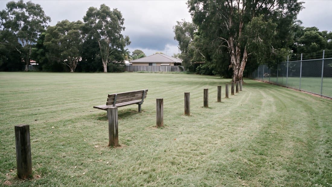 Illustrative after photo: the same bench and bollards with the grass mown short
