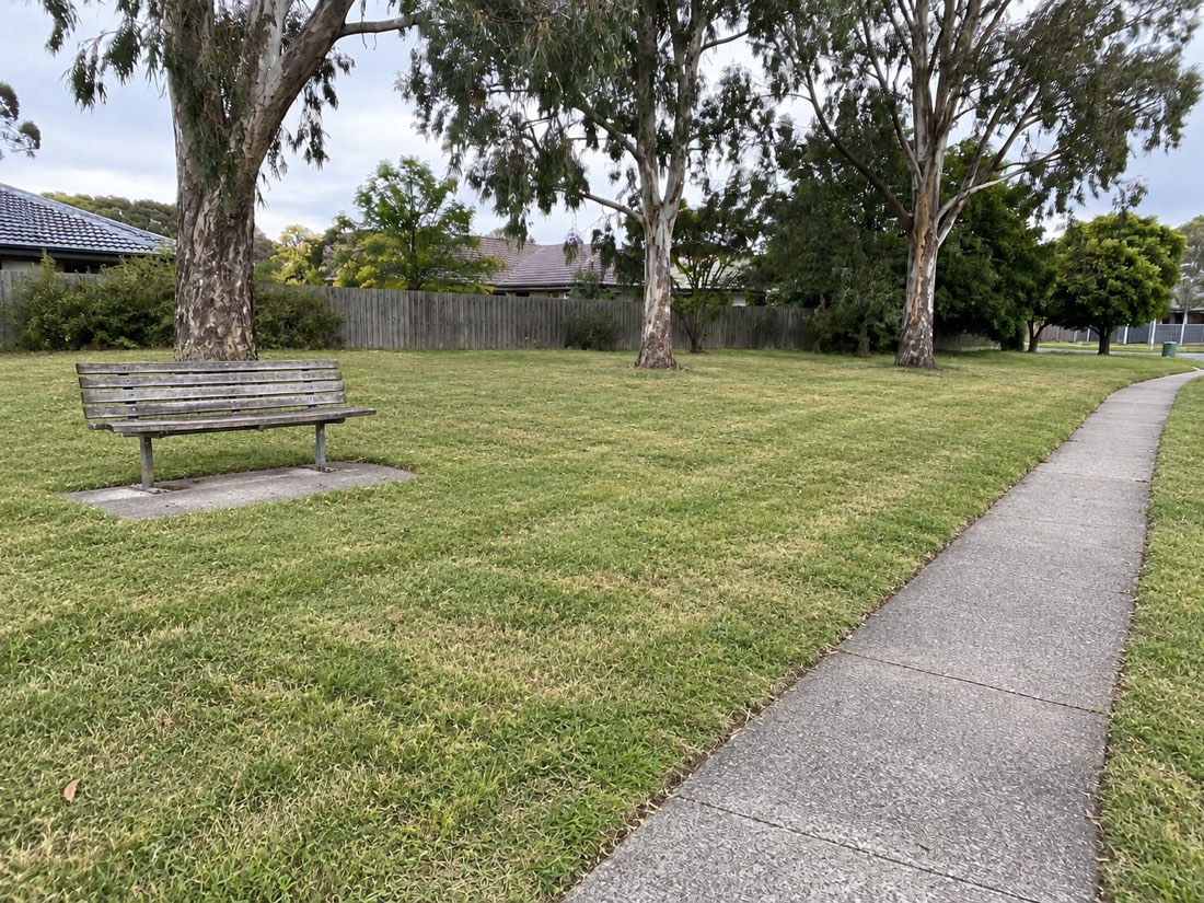 Illustrative after photo: the same bench and path with the grass mown and the edges trimmed